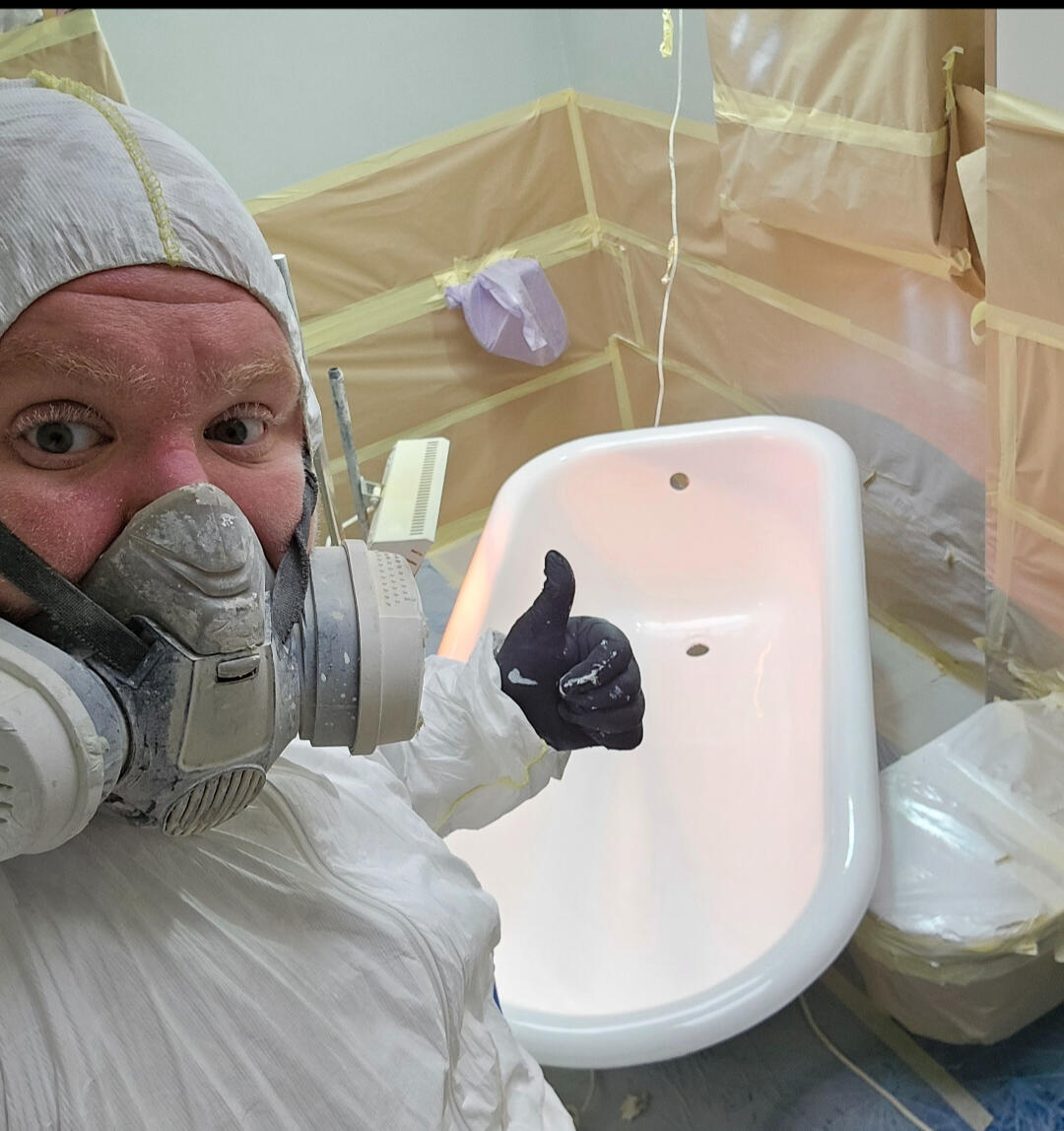 photo of glossy baths owner photo of glossy baths re-enamelling owner Seamus with a thumbs up, in ppe, in a room full of masking up and a completed bath in Cheltenham